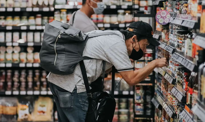 Dos hombres comprando en un supermercado, mirando las etiquetas