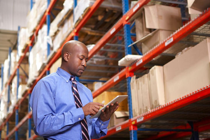 Contador realizando auditoría de inventario en el almacén, verificando existencias físicas y registros contables.