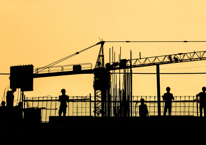 Silueta de trabajadores en una obra de construcción, representando actividad y dinamismo en proyectos industriales.